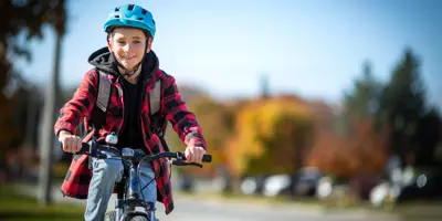 An 11-year old boy smiles as he rides a bike down a residential street