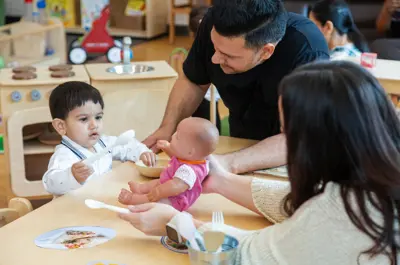 Man and woman playing with a young child who is pretending to feed a doll