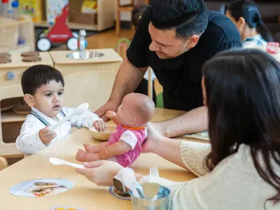 Man and woman playing with a young child who is pretending to feed a doll
