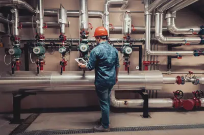 Person working in an industrial plant looking at water pipes