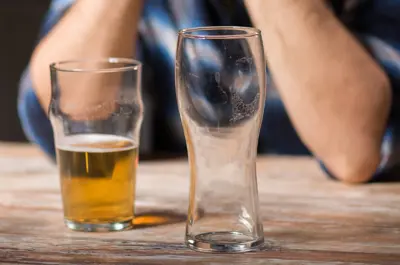 a person sitting at table with some empty and one partially full beer glass