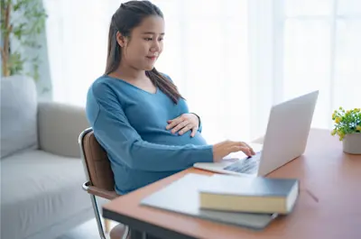 A pregnant woman sitting at a computer
